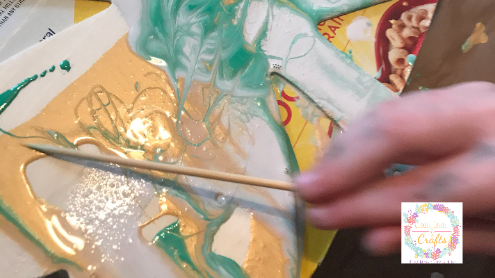 Using a skewer to make swirls in the paint pouring project