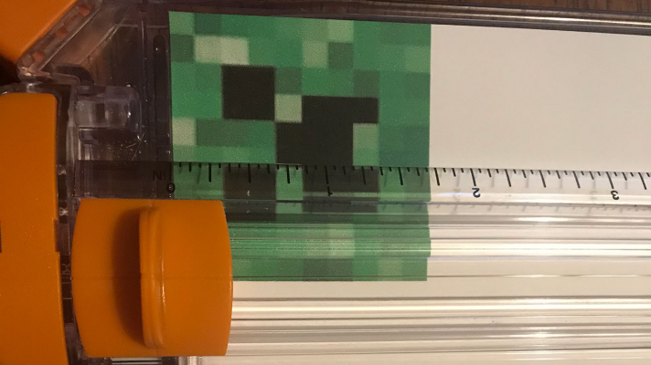 Cut out the creeper face with the paper trimmer or scissors to Mod Podge to the wooden dowel