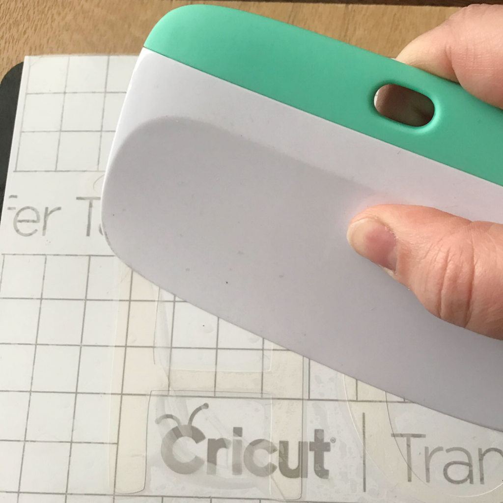 Using the Cricut Scraper to adhere the Smart Vinyl to the transfer tape